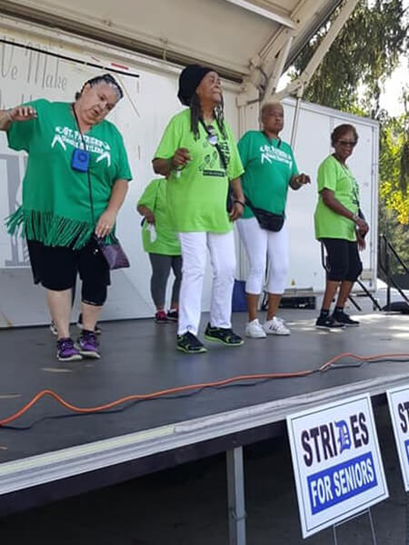 Volunteers in green shirts standing on stage and interacting with the audience.